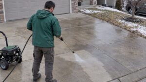 Homeowner pressure washing a concrete driveway